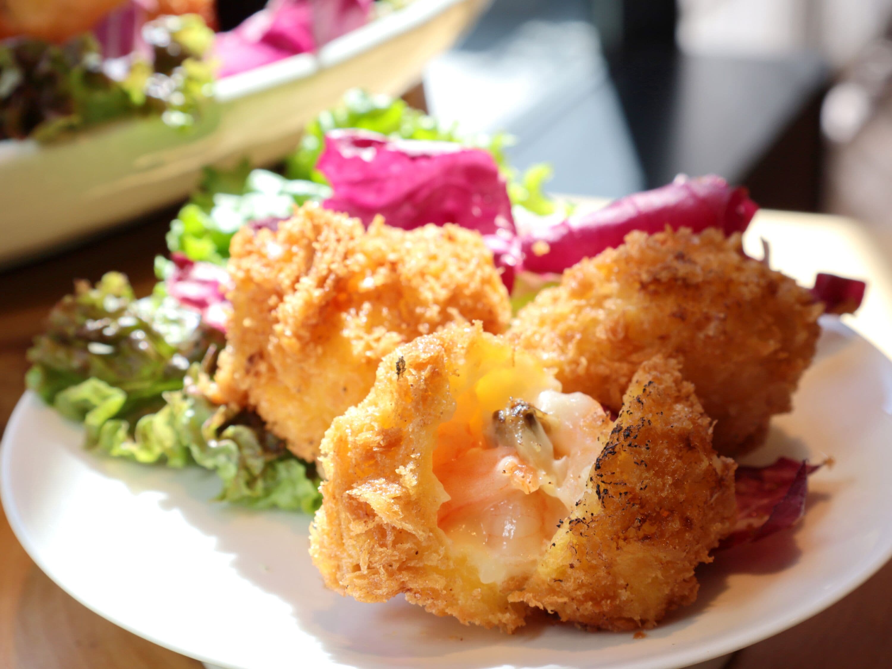 A plate with a breaded and fried food item, possibly chicken, with a visible egg yolk, accompanied by a side salad.