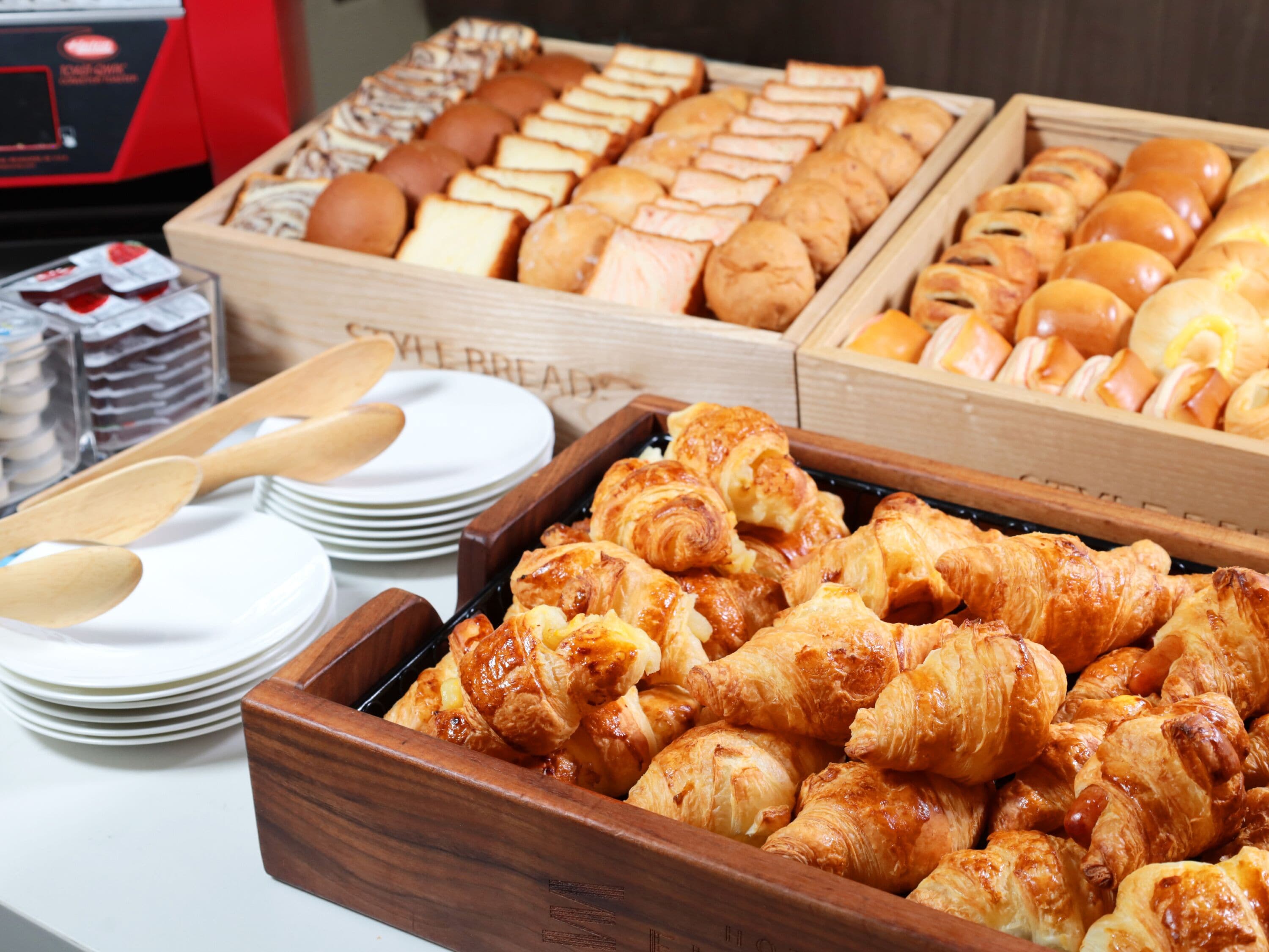 A buffet with various baked goods including bread, rolls, and pastries.