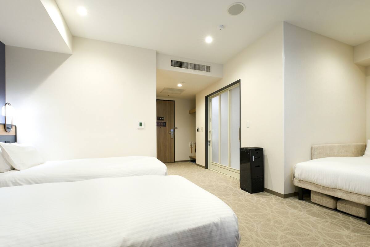 A hotel room with two beds, a desk, and a wardrobe.