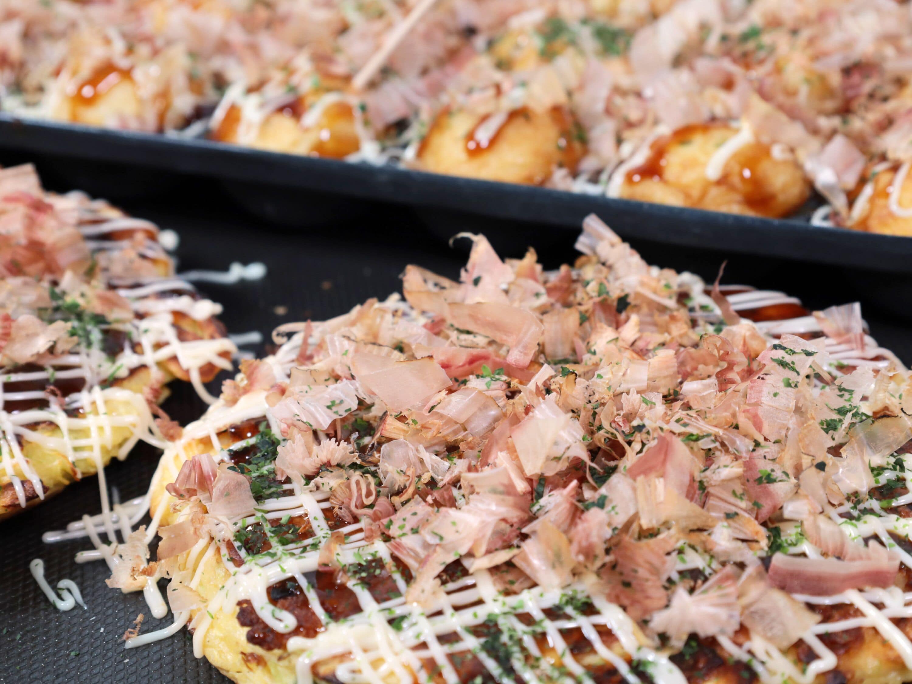 A close-up of a dish with shredded toppings, possibly a type of sushi or sashimi, garnished with herbs.