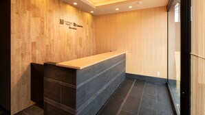 A reception area with a wooden wall, a reception desk, and a tiled floor. - Connect Inn Shichijokamogawa (Kyoto)