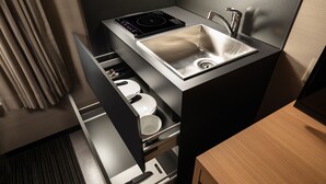 A compact kitchen with a built-in sink, a stovetop, and a drawer with utensils. - Connect Inn Shichijokamogawa (Kyoto)
