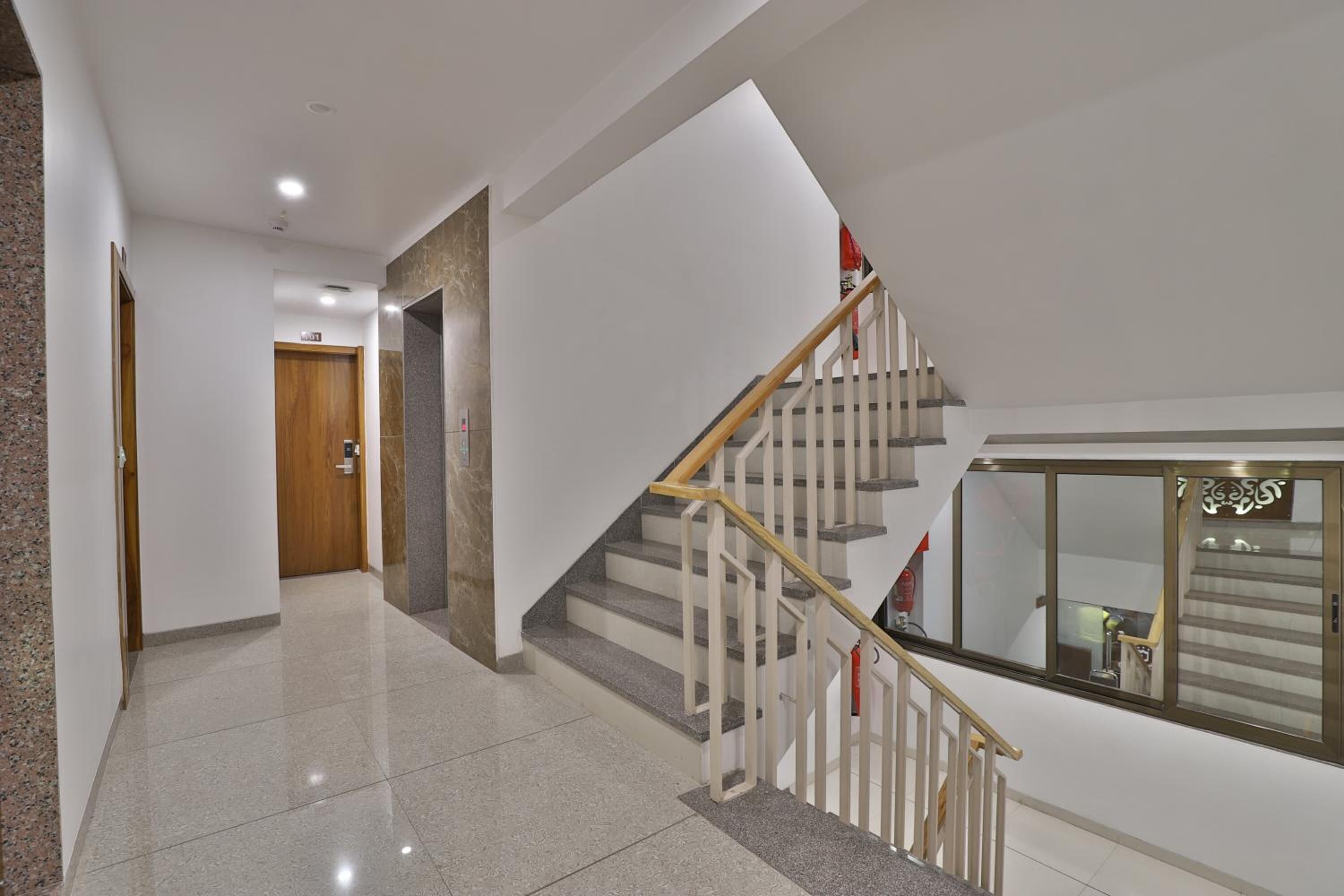 Een modern interieur met een trap, gepolijste vloeren en een houten deur.