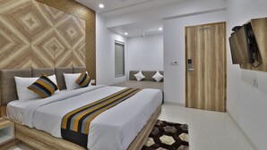 A modern bedroom with a large bed, a wooden headboard, a ceiling fan, and a wooden door. - Hotel Le Grand (Surat)