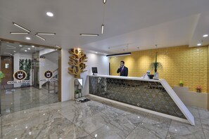 Zona de recepción de un hotel con diseño moderno, que incluye un mostrador de recepción, una escultura decorativa de un árbol y un mostrador de registro.