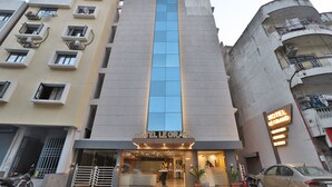 A hotel with a prominent vertical blue glass facade, a sign reading "HOTEL LE GRAND," and a neon sign on the adjacent building. - Hotel Le Grand (Surat)