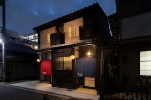 A traditional building with a tiled roof, a black gate, and a red sign. - Kanade Kujoaketachobettei (Kyoto)
