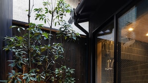 A modern building with a wooden fence, a small tree, and a garden area with pebbles and plants. - Kanade Kujoaketachobettei (Kyoto)