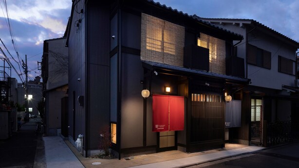 A traditional Japanese-style building with a dark facade, large windows, and a red entrance sign. - Kanade Kujoaketachobettei (Kyoto)