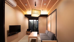 A modern living room with a sofa, a table, and a flat-screen TV mounted on the wall. - Kanade Kujoaketachobettei (Kyoto)