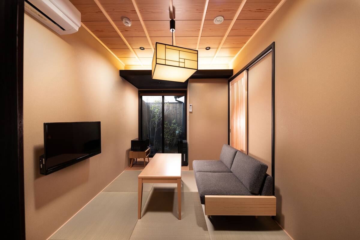 Een moderne woonkamer met een bank, een tafel en een flatscreen televisie aan de muur.