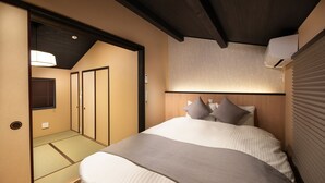 A hotel room with a bed, a bedside table, a lamp, and a window with blinds. - Kanade Kujoaketachobettei (Kyoto)