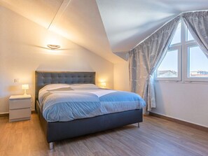 Una camera da letto moderna con un letto grande, lampade ai comodini e vista attraverso una finestra con tende.
