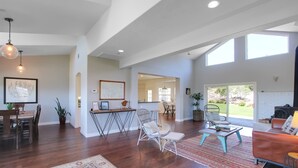 Amplia sala de estar con pisos de madera, una mesa de comedor y una zona de estar con sofá y sillones.