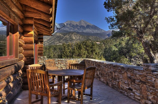 A wooden log cabin with a stone wall and a stone patio.