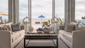 A modern living room with a view of the beach and ocean through large glass doors.