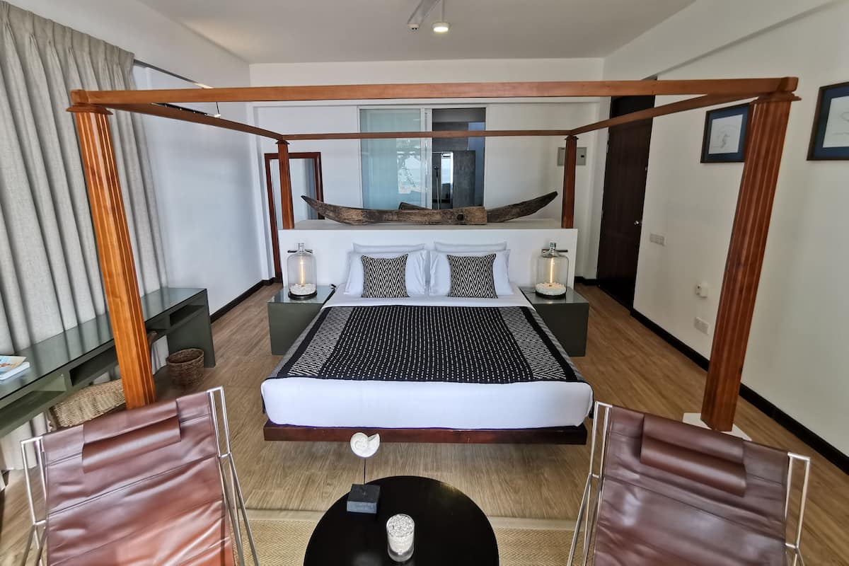 A modern bedroom with a four-poster bed, a hammock, and a view of the city.