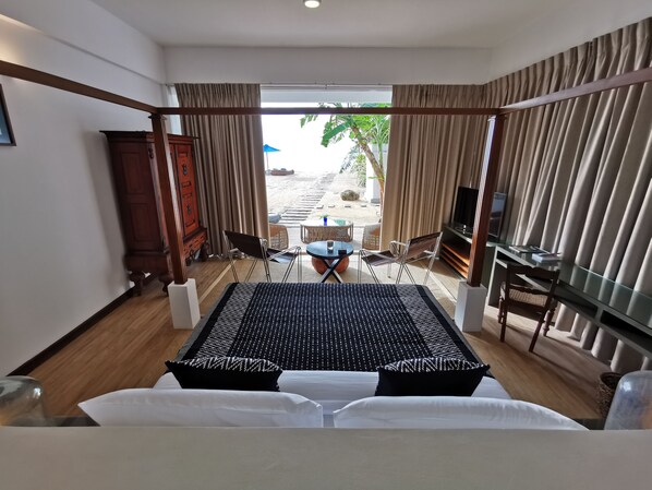 Habitación de hotel con cama, televisión, mesa de comedor y vistas al exterior.