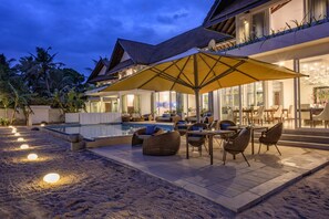 A poolside area with outdoor seating and a large umbrella. - The Beach House by Reveal (Kamburugamuwa)