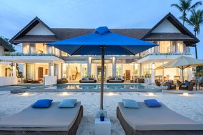 Un resort con piscina, sillas de descanso y una sombrilla grande.
