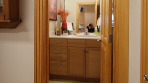 A hallway leading to a bathroom with wooden cabinets, a sink, and a mirror. - Cozy Studio apartment with a Courtyard  (North Pole)