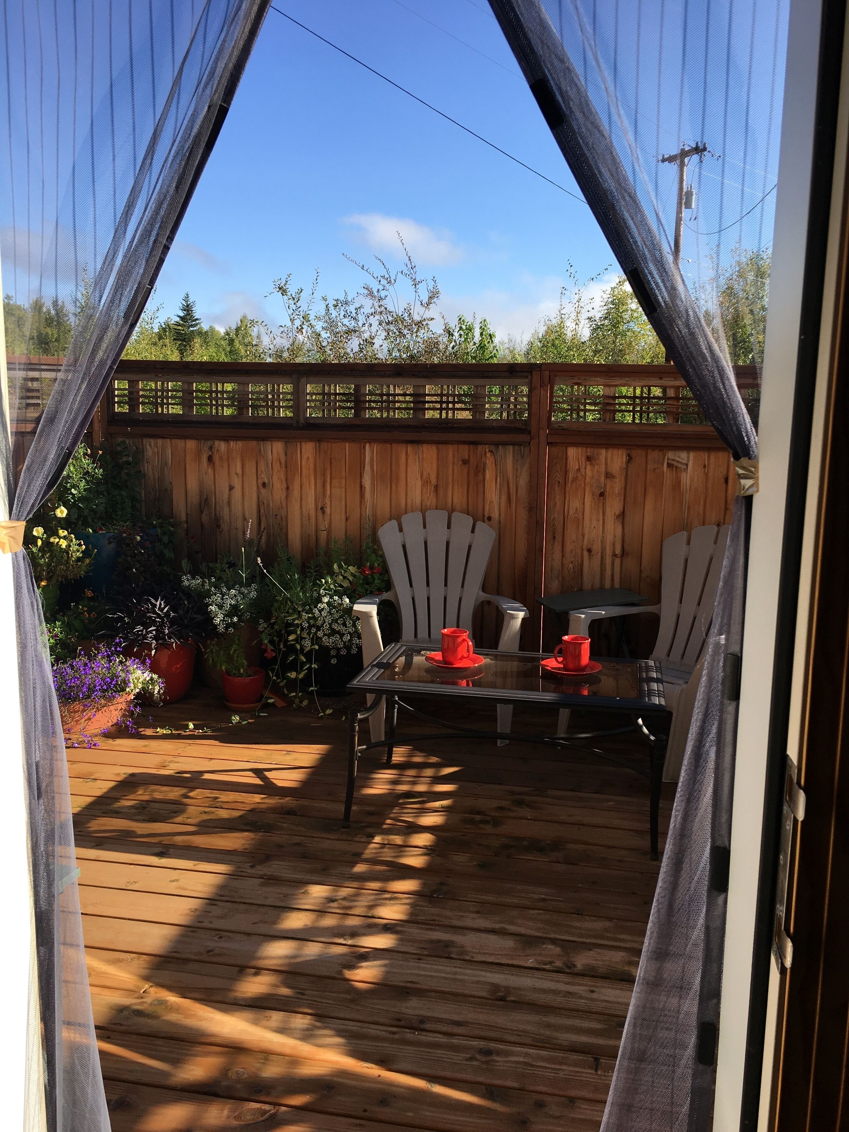 Eine Terrasse im Freien mit Holzdeck, Tisch und Stühlen sowie Blumentöpfen.