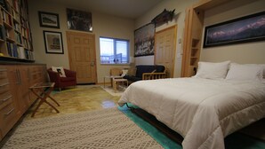 A bedroom with a bed, a desk, a chair, a bookshelf, and a window. - Cozy Studio apartment with a Courtyard  (North Pole)