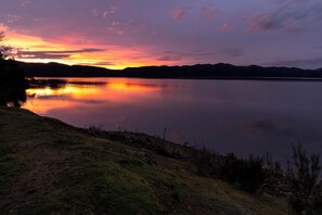 A calm lake at sunset with a visible shoreline and distant hills. - Reflections Burrinjuck Waters - Holiday Park (Burrinjuck)