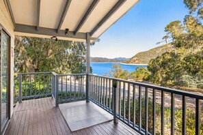 A wooden deck with a metal railing, overlooking a coastal landscape with trees and a clear blue sky. - Reflections Burrinjuck Waters - Holiday Park (Burrinjuck)
