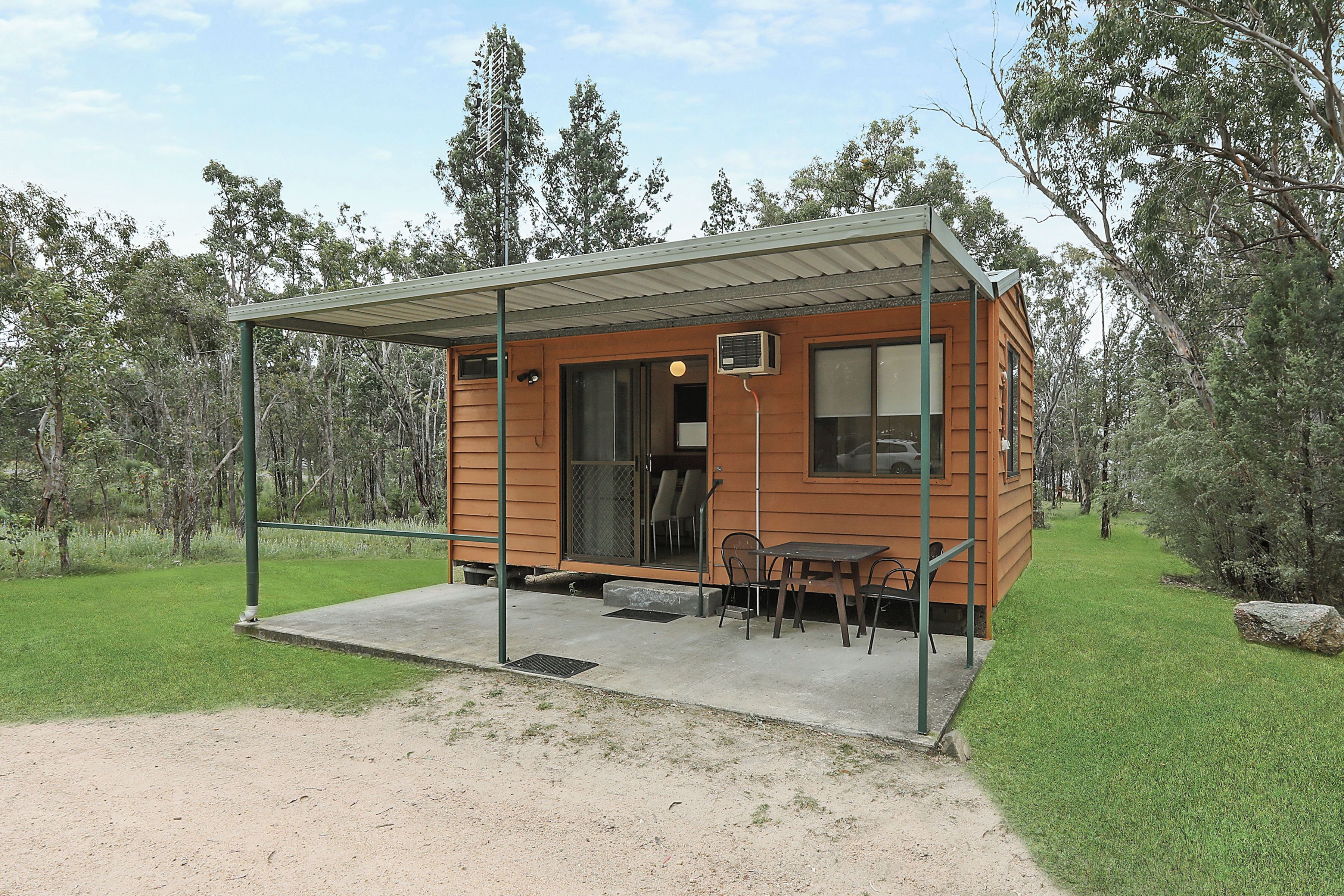 Eine kleine Holzhütte mit einer überdachten Veranda, einem Tisch und Stühlen.