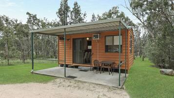 Eine kleine Holzhütte mit einer überdachten Veranda, einem Tisch und Stühlen.