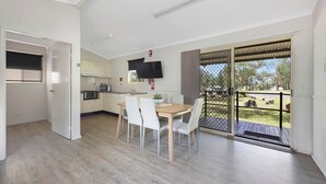 Una cocina moderna con armarios blancos, una mesa de comedor de madera y un televisor montado encima.