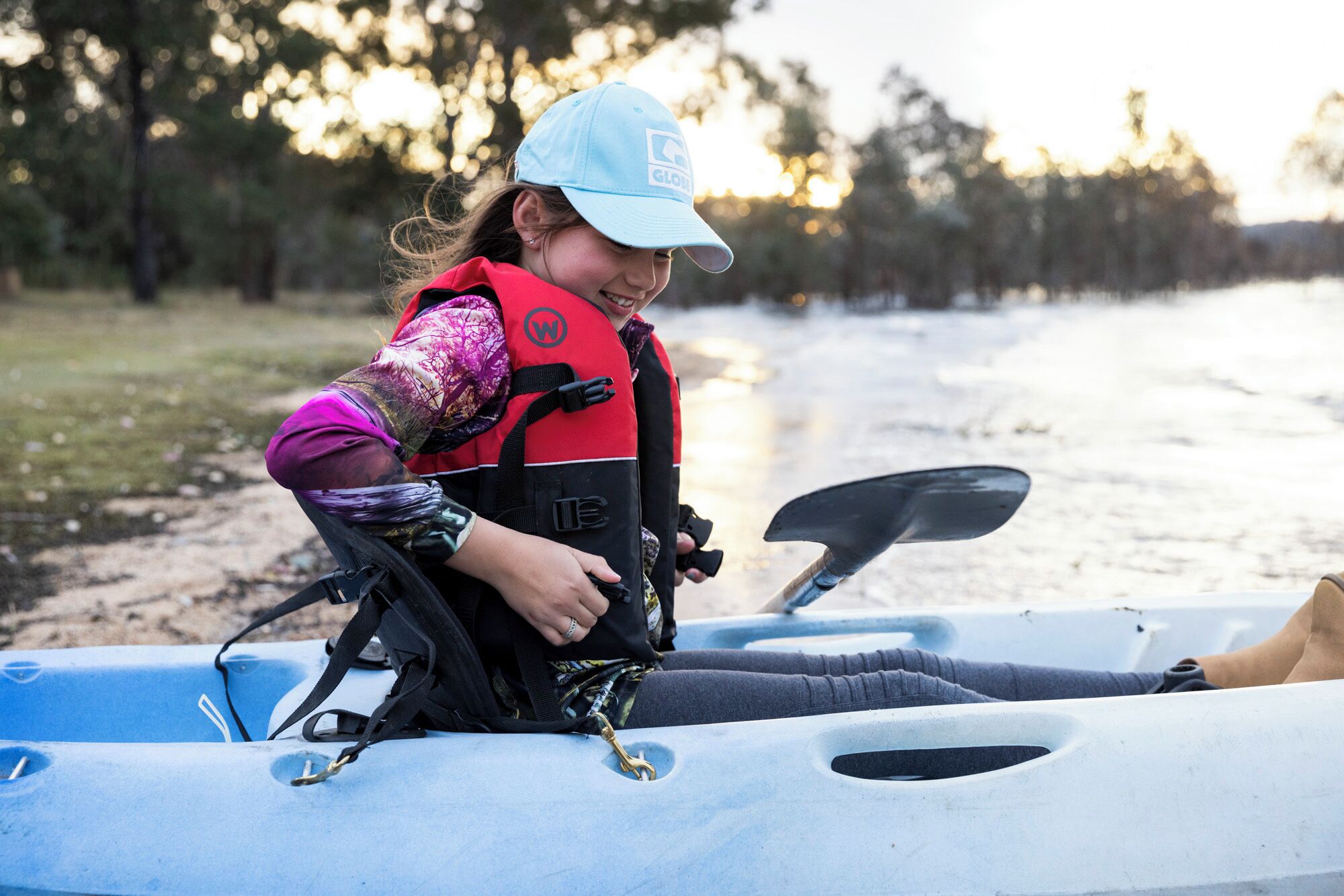 A person in a kayak with a life jacket, preparing to paddle.