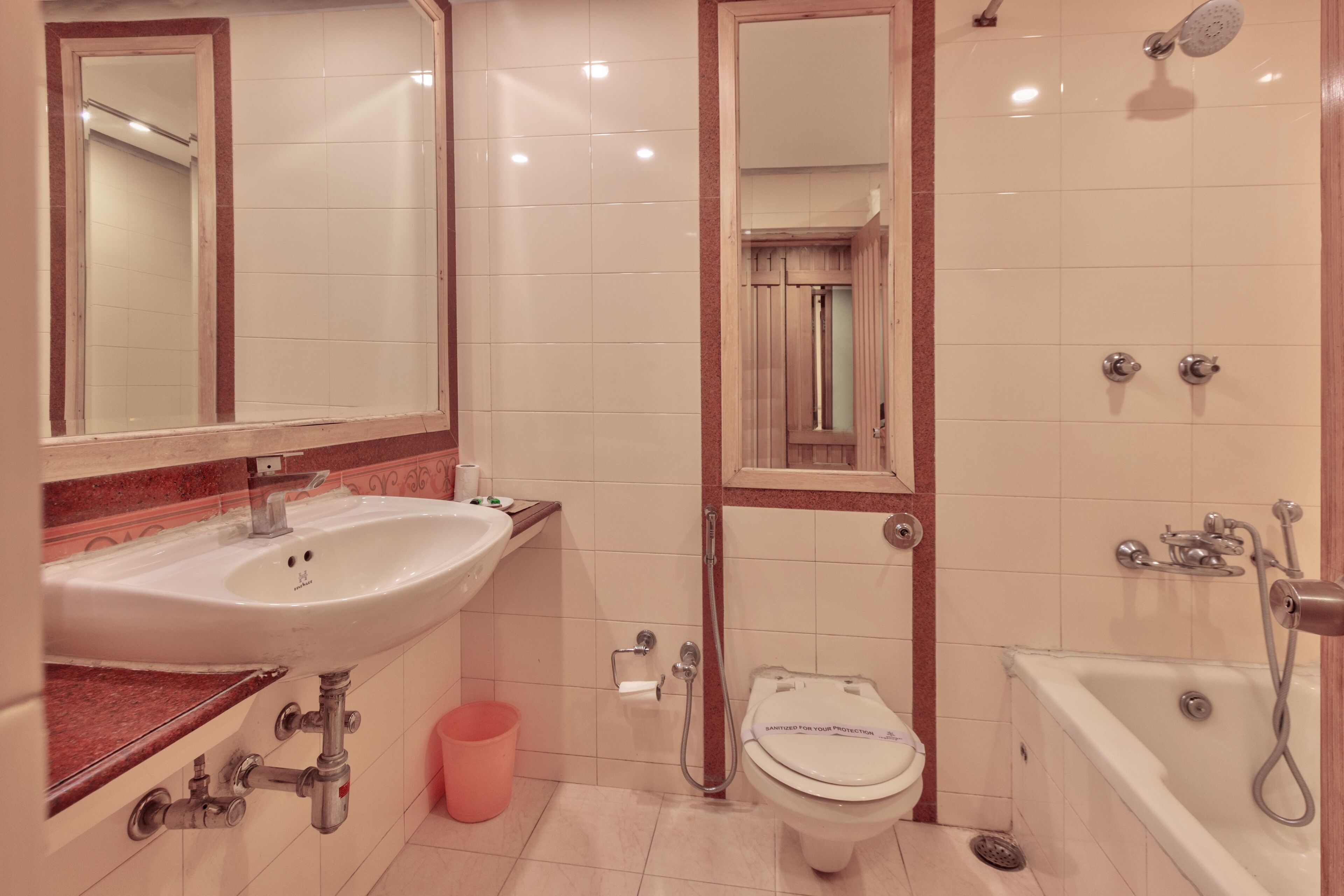 A bathroom with a sink, toilet, and bathtub, featuring a mirror, tiled walls, and a shower.