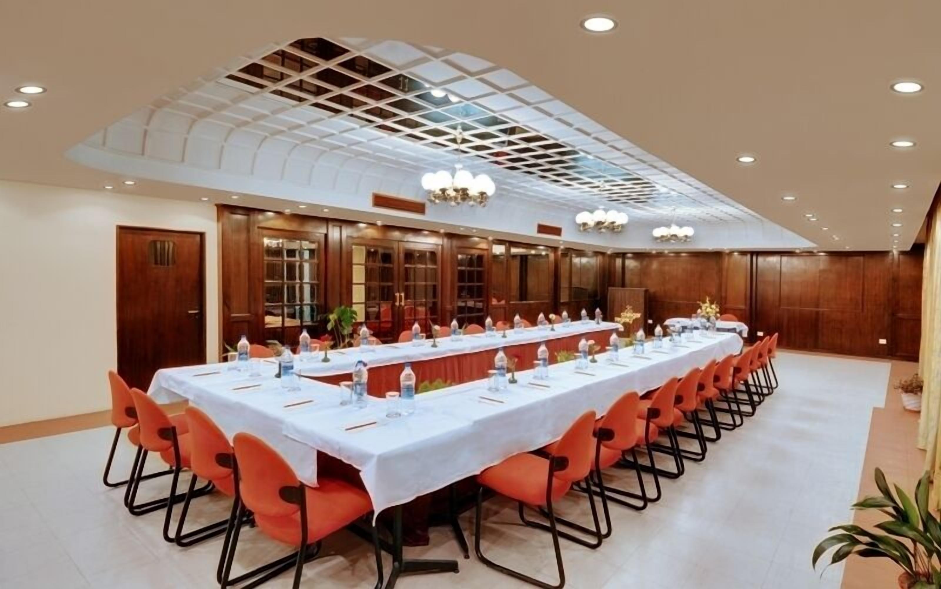 A conference room with a long table, orange chairs, and a ceiling with a grid pattern.