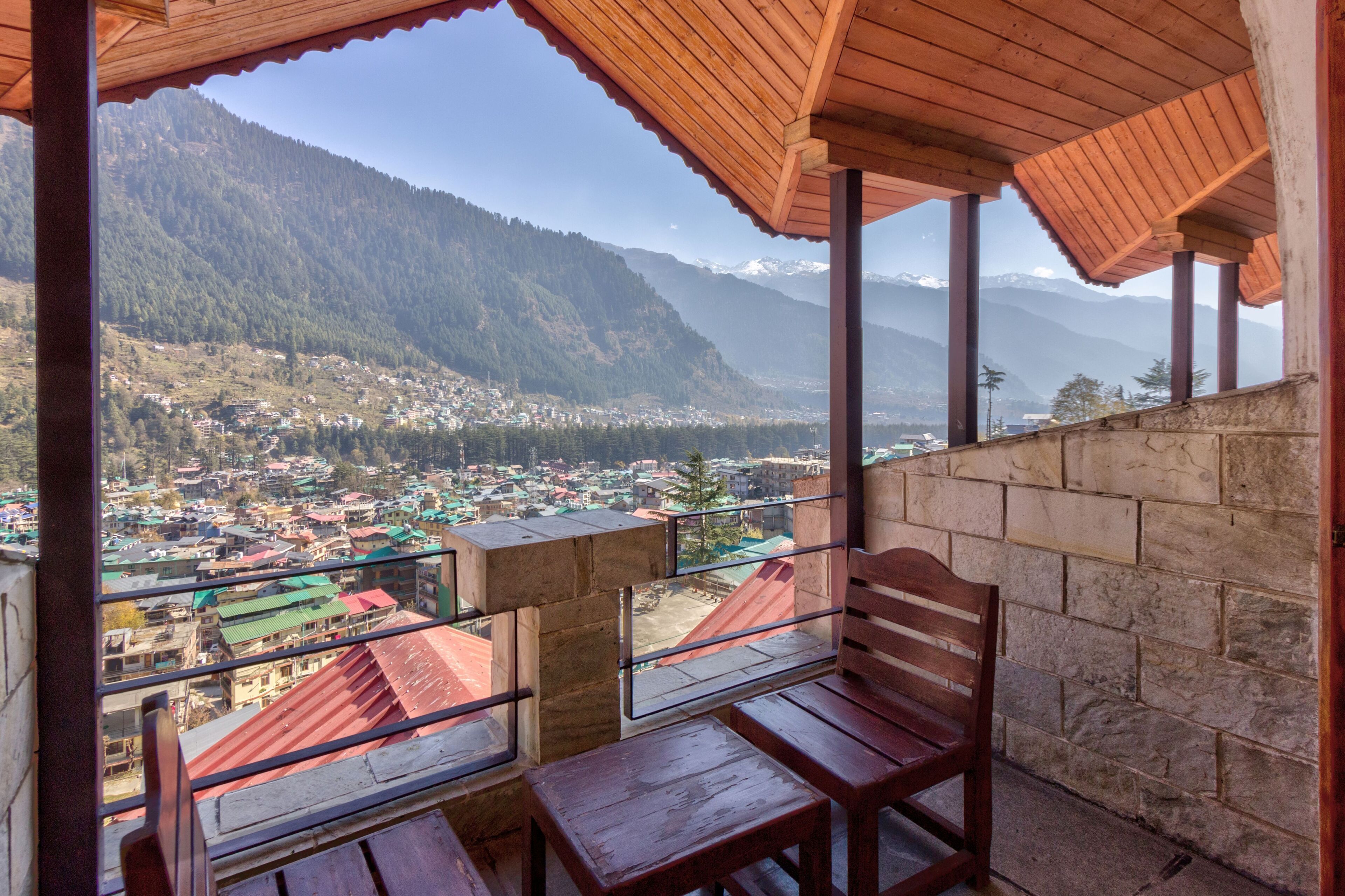 A wooden balcony with a view of a town and mountains.