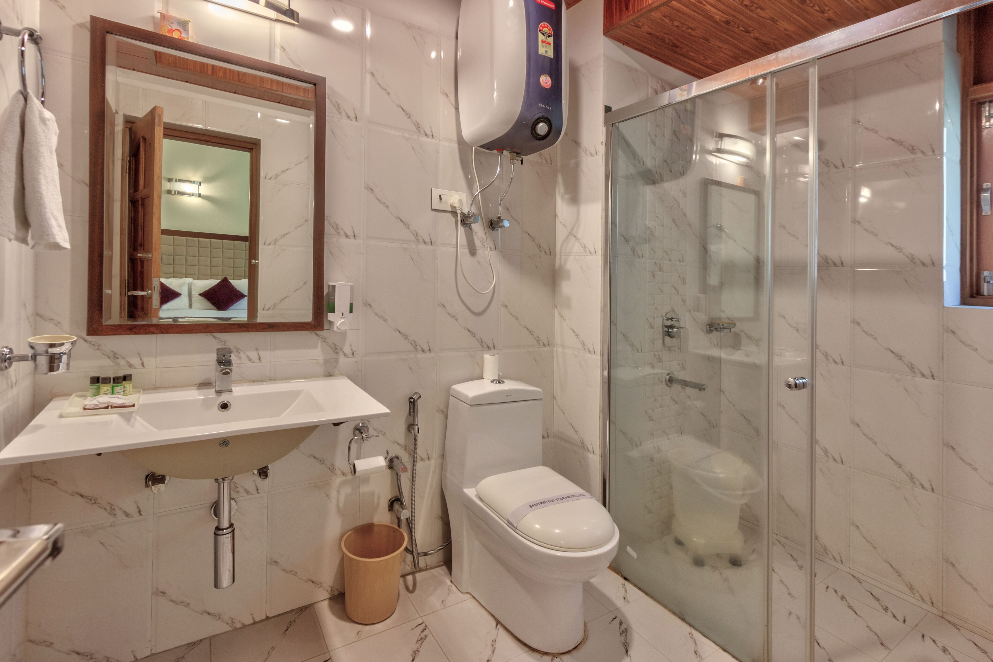 A bathroom with a marble sink, a toilet, and a glass-enclosed shower.