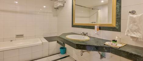 Un baño moderno con bañera, lavamanos y un espejo grande.