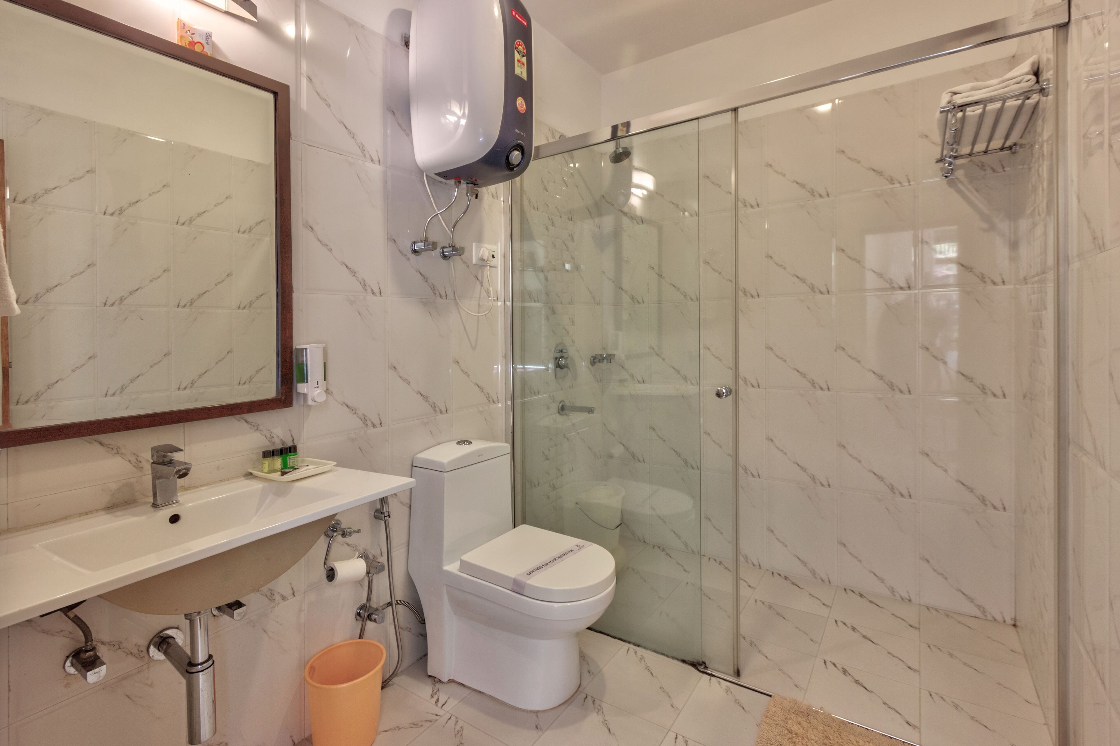 A modern bathroom with a glass-enclosed shower, a white toilet, and a sink with a mirror above it.