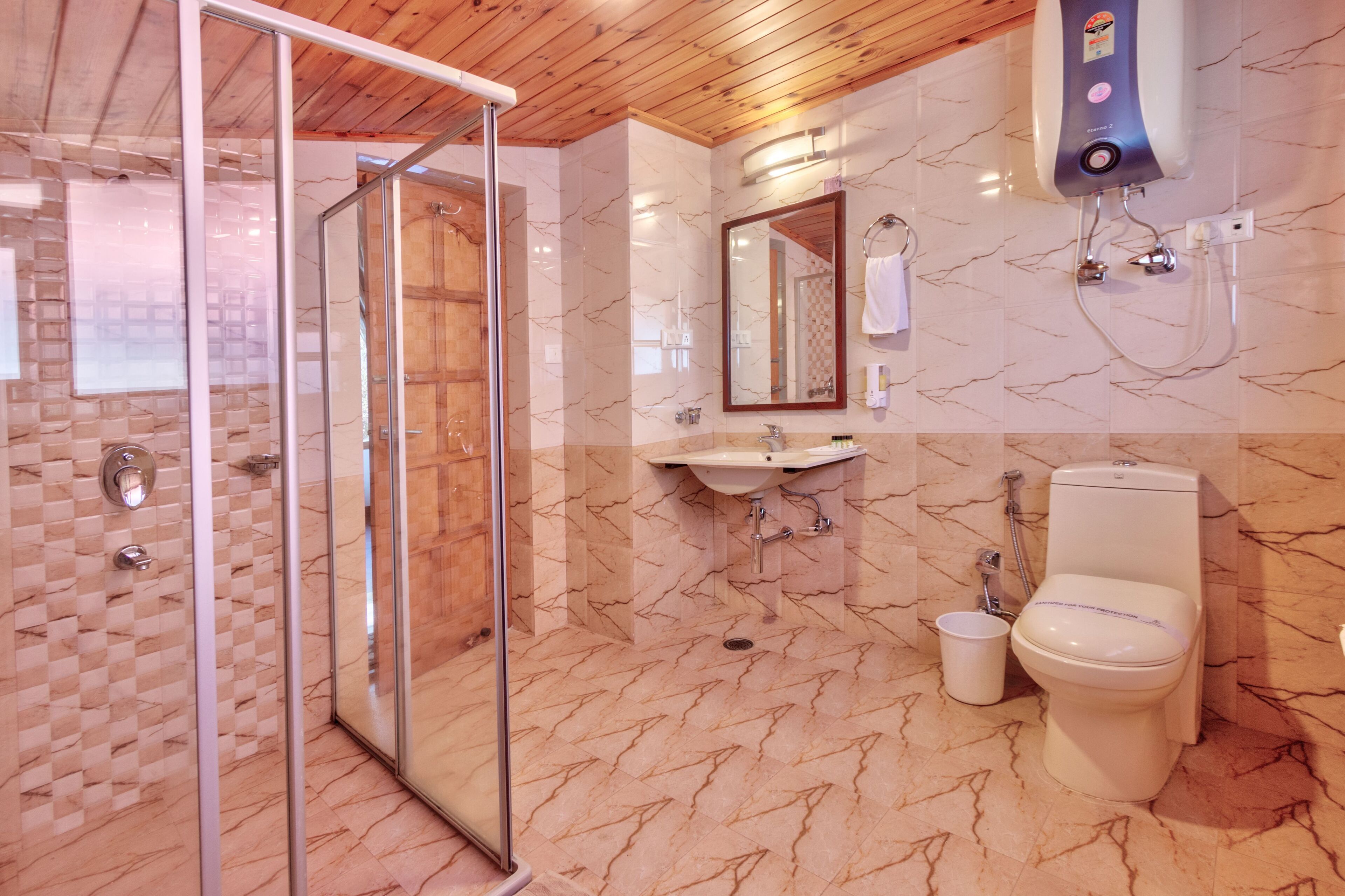 Een badkamer met een douchecabine van glas, een wastafel, een toilet en een handdroger.