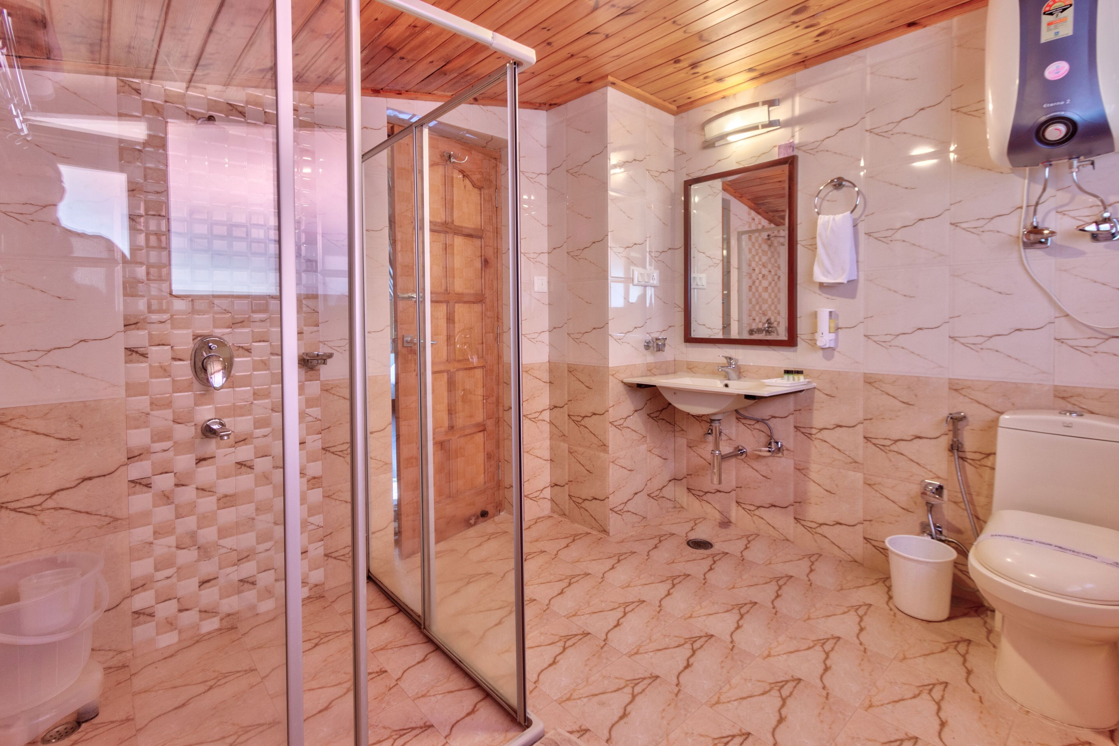 A bathroom with a glass-enclosed shower, a sink, a toilet, and a mirror.