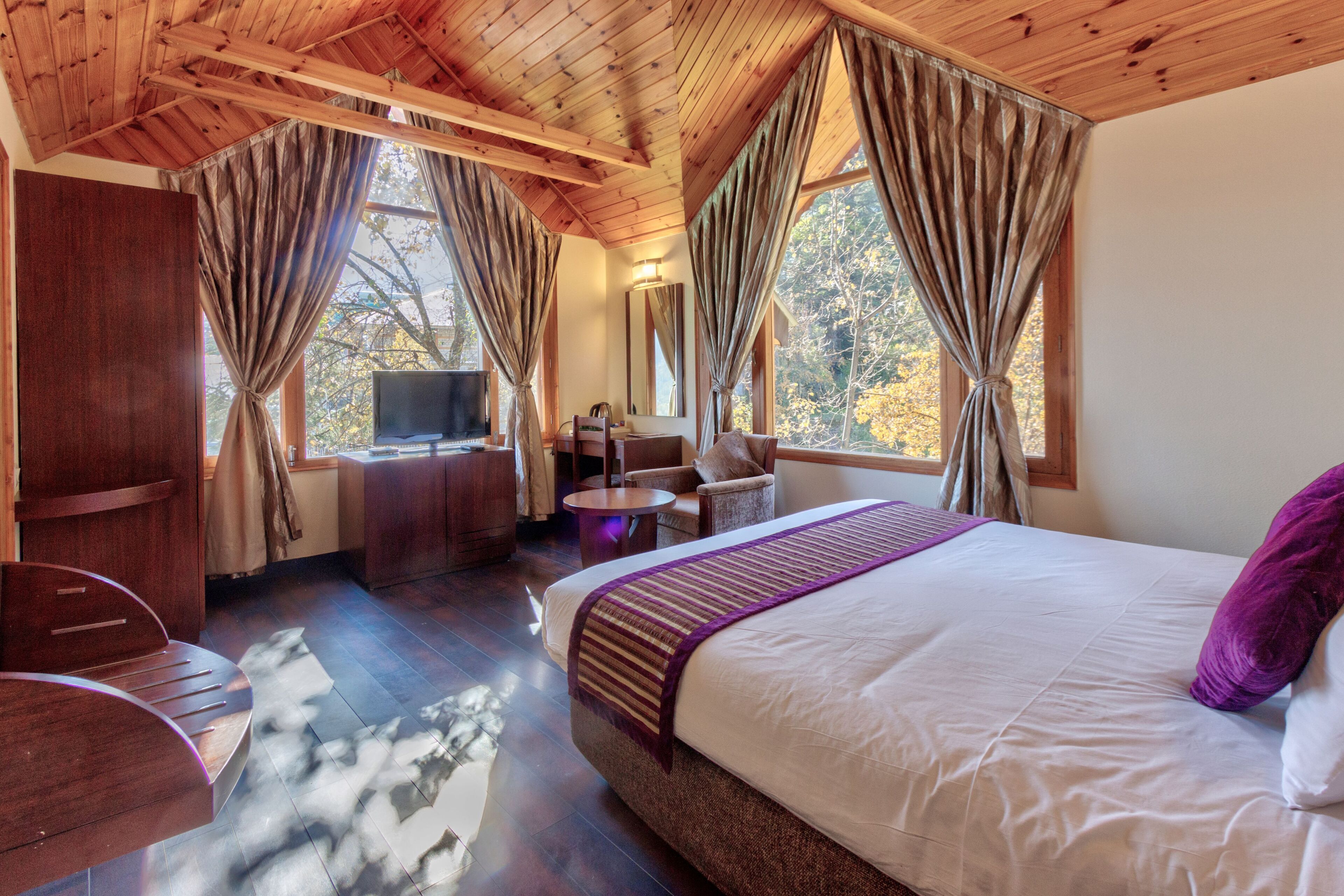 A bedroom with a large bed, a desk, and a TV.