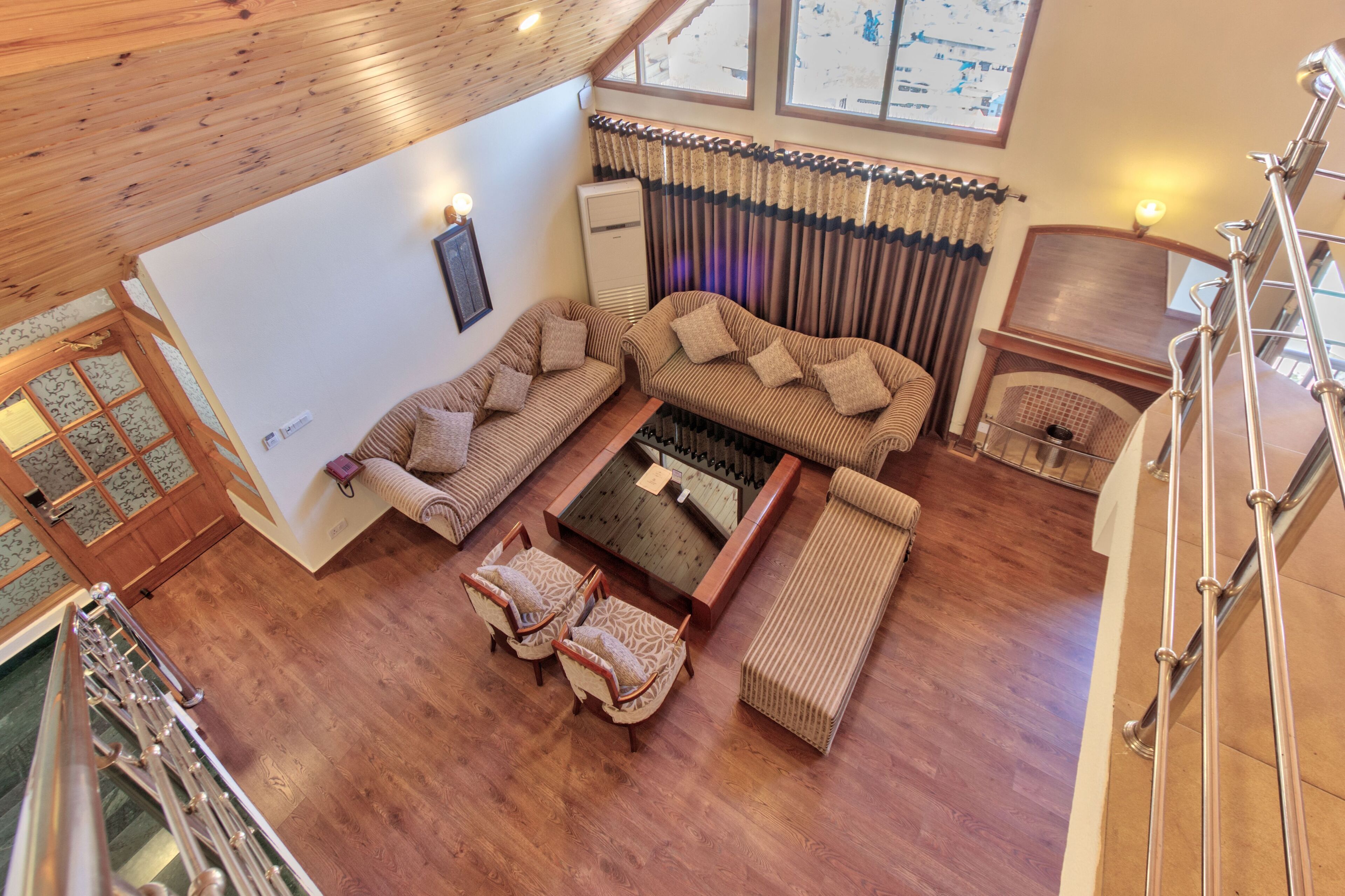 A spacious living area with a wooden ceiling, a fireplace, and a large window with curtains.