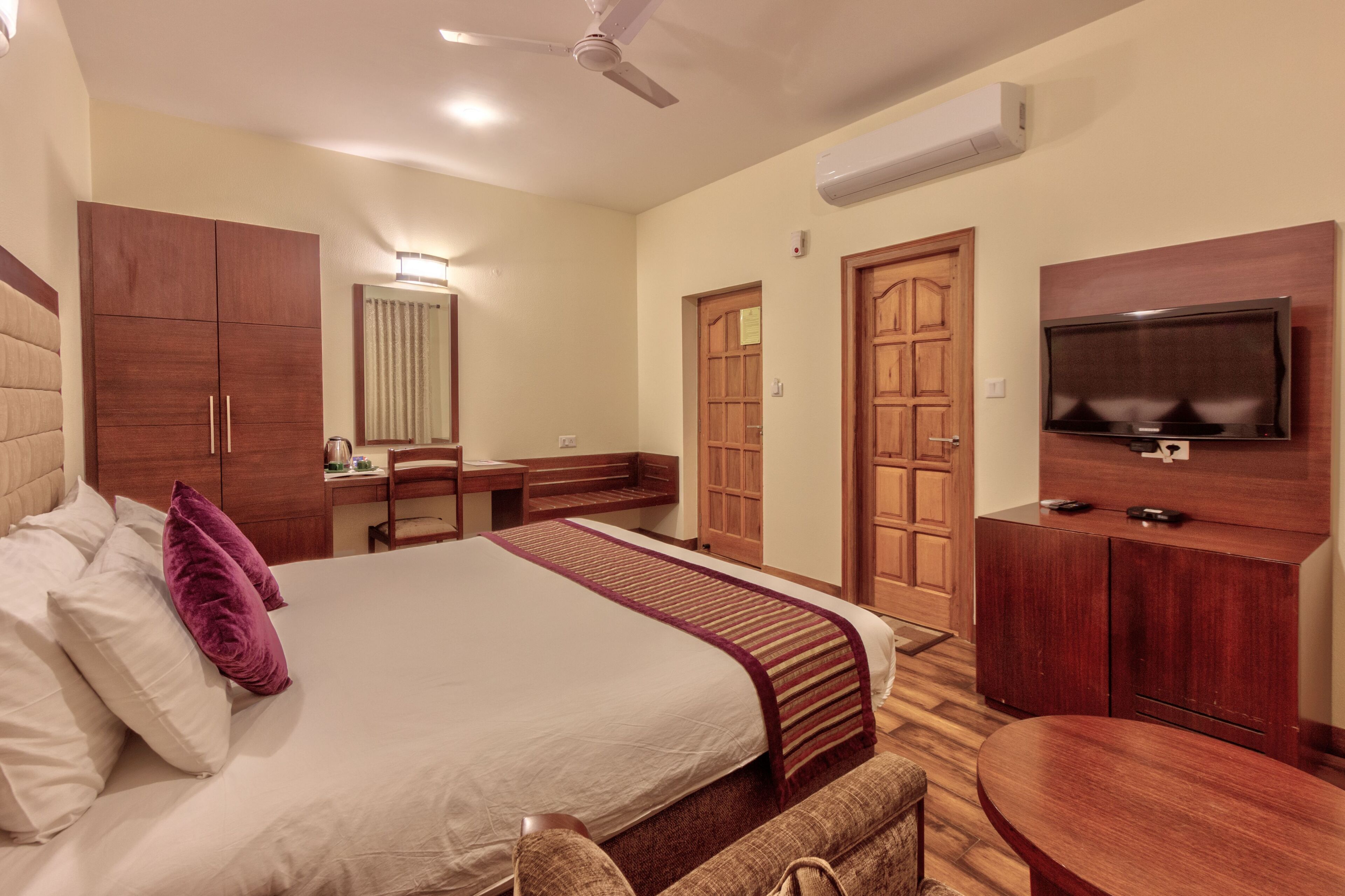 Una habitación de hotel con cama, escritorio, silla, televisor y armarios de madera.
