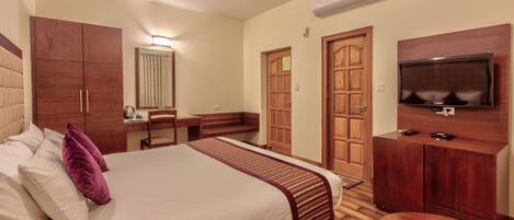 Una habitación de hotel con cama, escritorio, silla, televisor y armarios de madera.