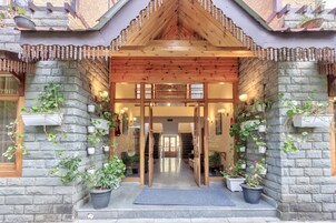 A stone building with a wooden entrance, potted plants, and a staircase leading inside.
