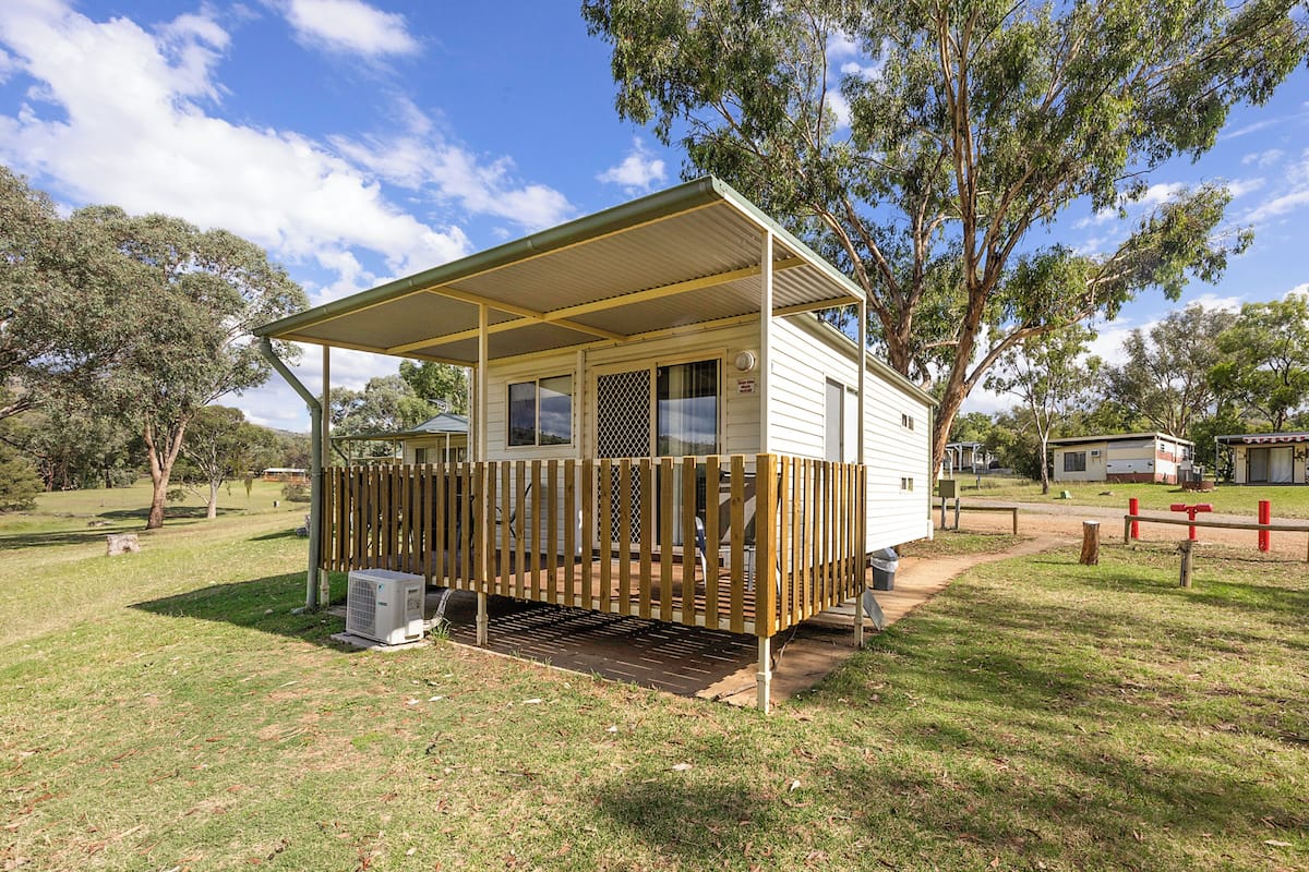 A mobile home with a covered porch and a fenced yard.