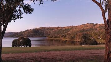 A lake surrounded by hills with a few trees and a small structure in the distance.