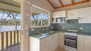 A kitchen with a view of a lake, a gas stove, a sink, and cabinets. - Reflections Grabine Lakeside - Holiday Park (Bigga)