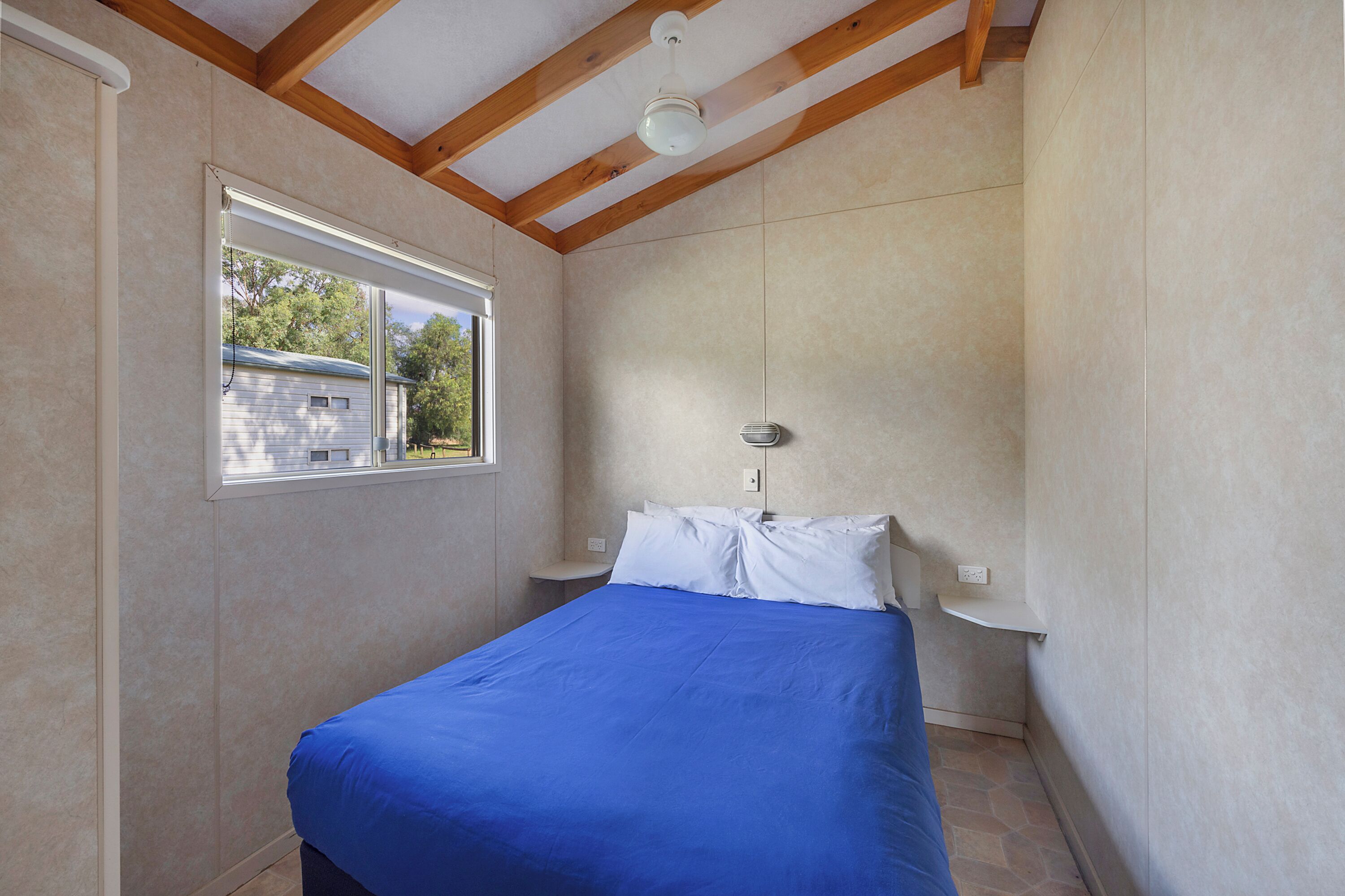 Un dormitorio con cama, ventana y ventilador de techo.